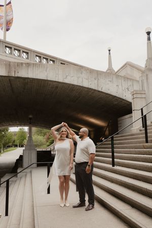 A couple dances together on concrete stadium-style steps under an architectural overhang.