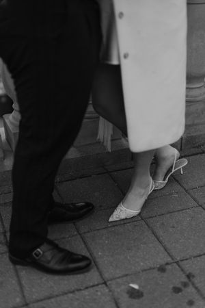 Black and white image of contrasting formal footwear showing a men's dress shoe next to a women's kitten heel pump.