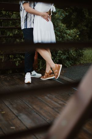 Close-up of feet and legs during an intimate moment on a wooden bridge.