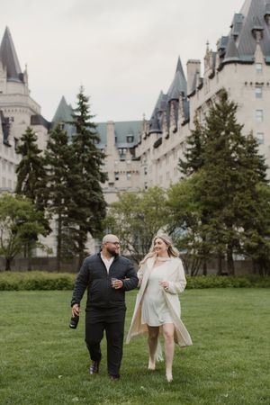Couple walking on a lawn with the majestic Chateau Frontenac castle in Quebec City as a backdrop.