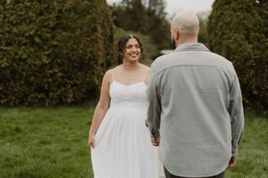 A bride and groom share an intimate moment together while walking through a lush garden setting.
