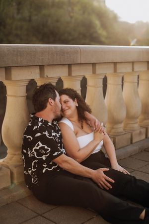 An intimate moment shared between couple on stone balustrade at golden hour.