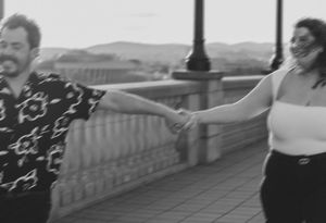 A playful moment captured in motion on a bridge against a scenic background.