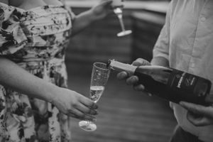 Champagne being poured into glasses at an outdoor gathering.