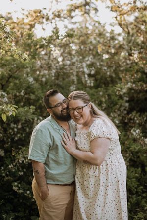 A couple sharing an intimate moment among flowering trees in a garden setting.