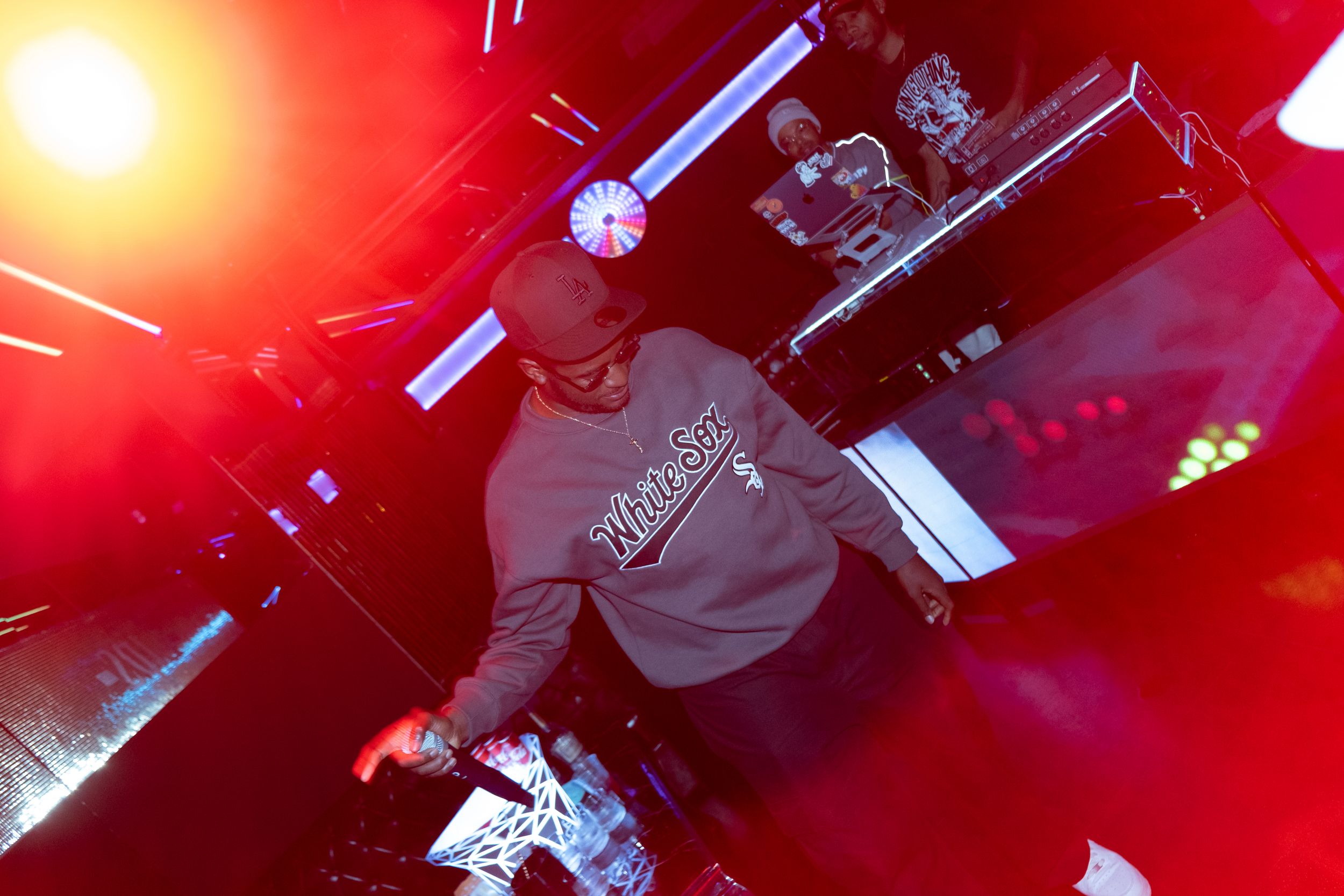 DJ performing on stage with red lighting effects and dramatic atmosphere during a nightclub performance.