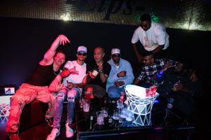 Group of performers on stage at nightclub with colorful lighting effects.