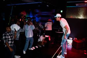 People dancing and enjoying music at a nightclub with colorful lights and neon ambiance.
