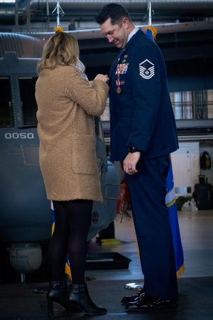 Intimate moment between service member in dress blues and person in tan coat during ceremony.