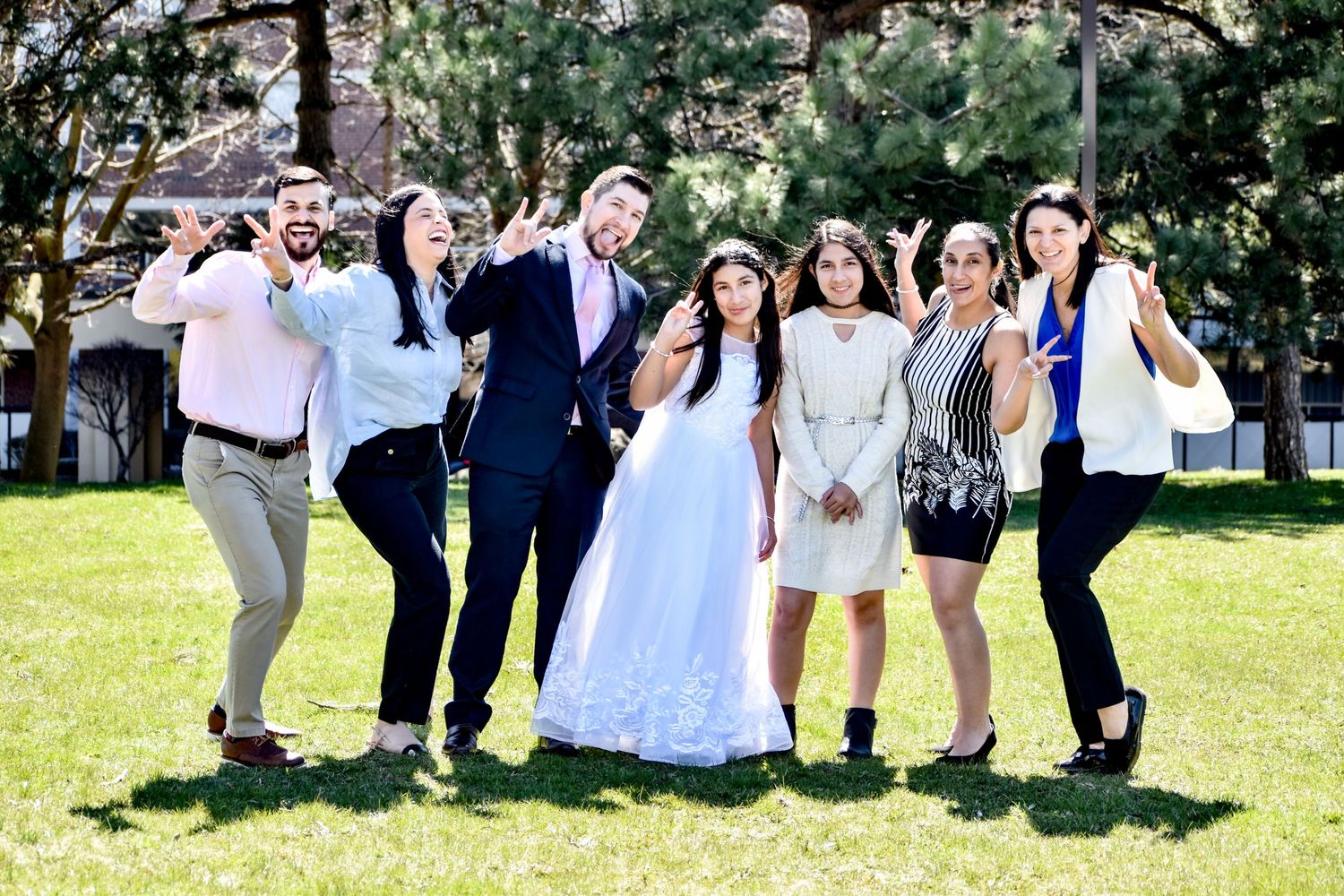Joyful wedding party group posing together on green grass outdoors with bride in white gown. Toronto GTA