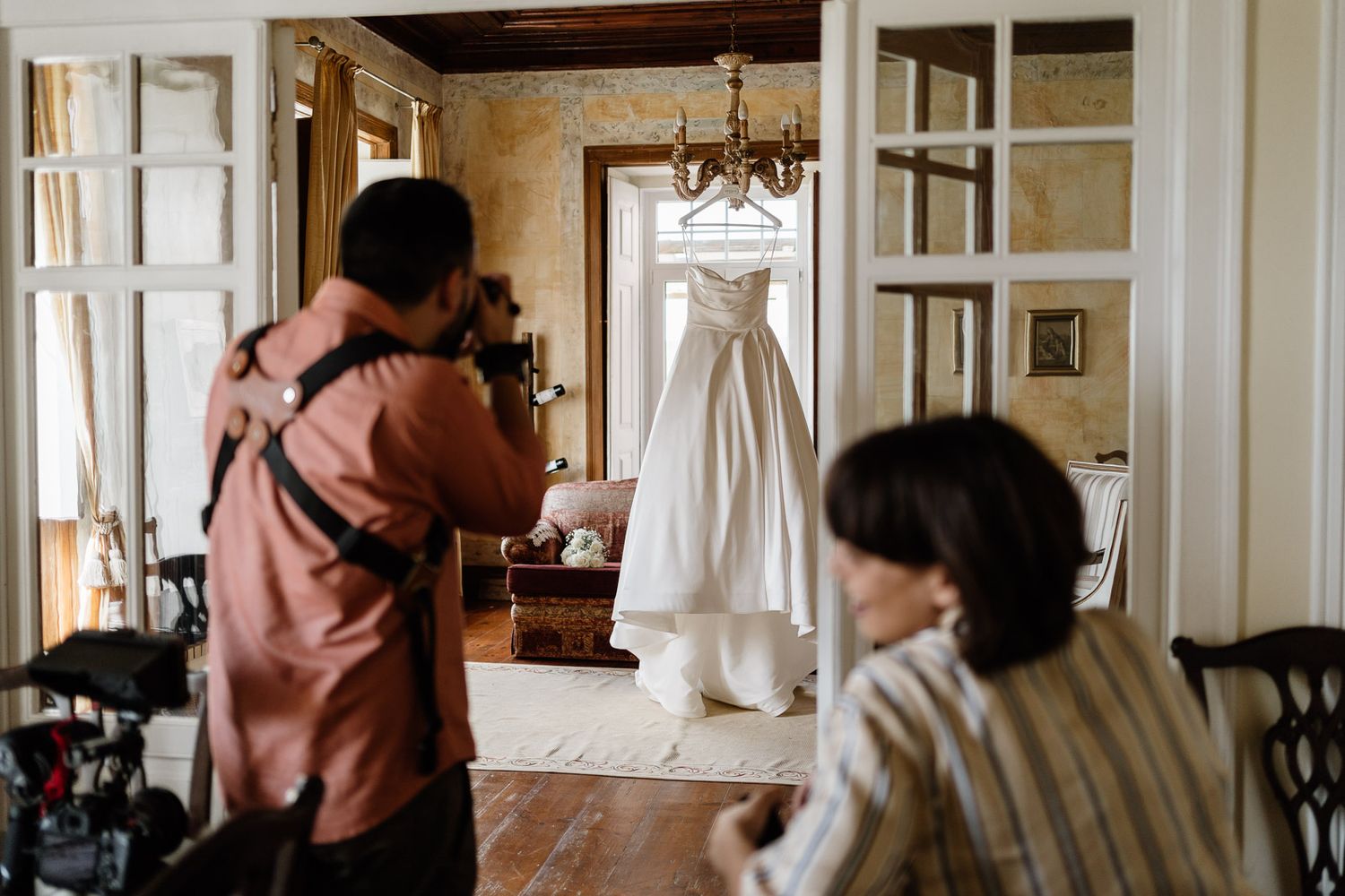 Interior room with wedding dress hanging and natural light streaming through windows.