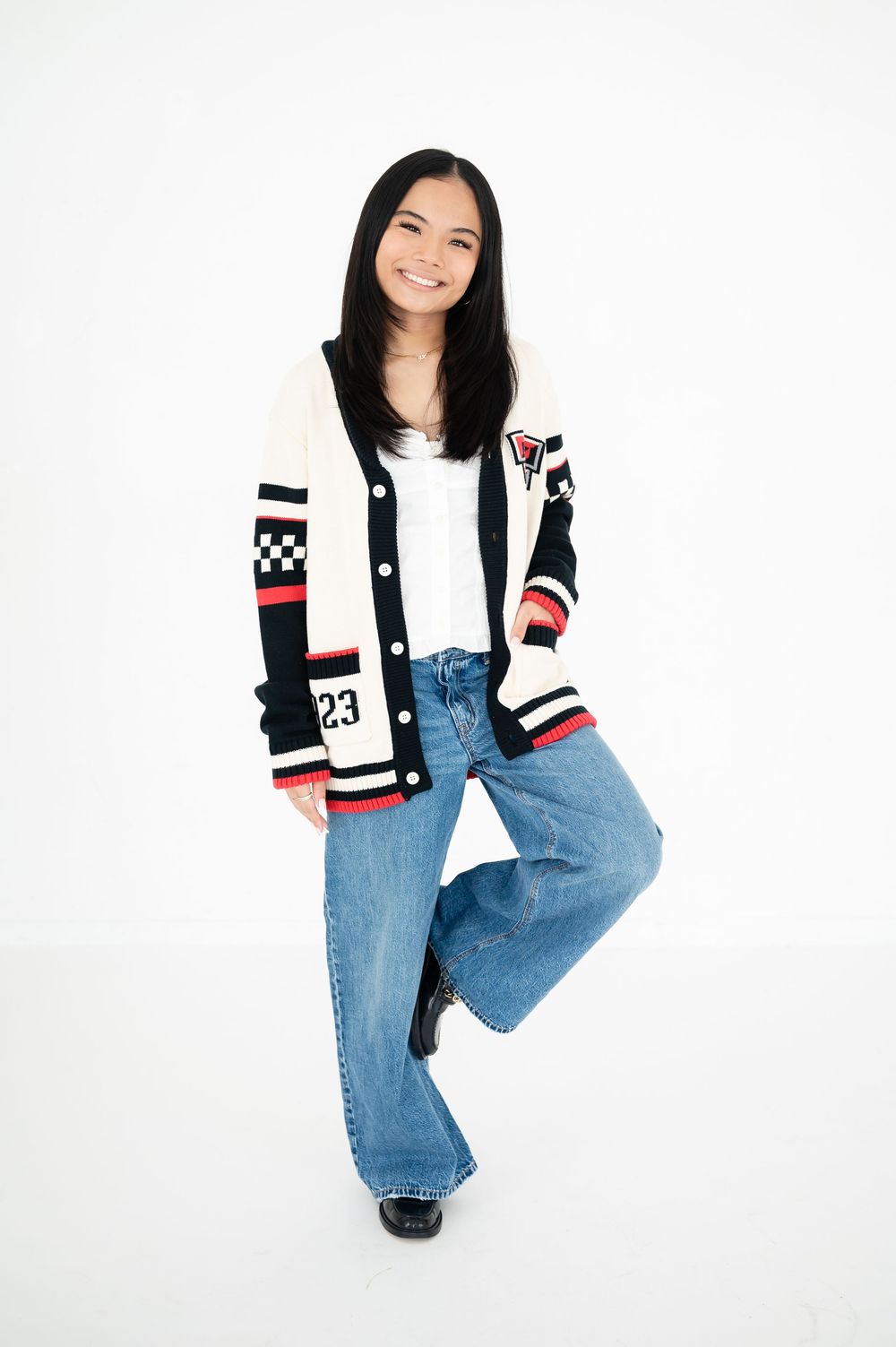 Person wearing patterned cardigan and wide-leg jeans against white background.