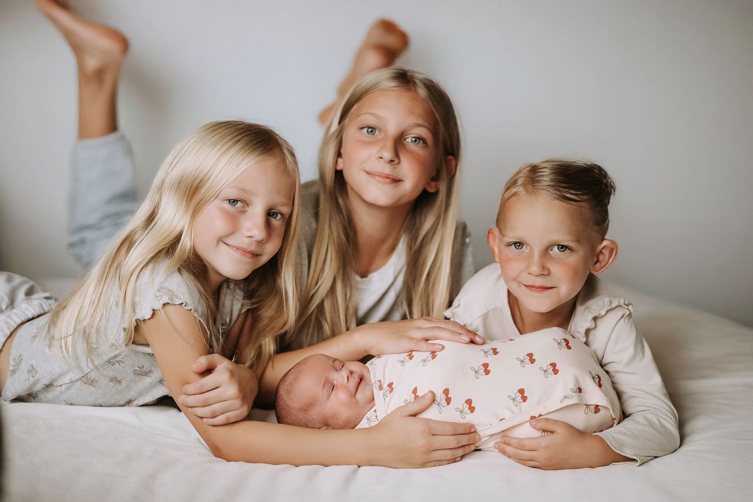 Siblings gathered closely together on light gray background.