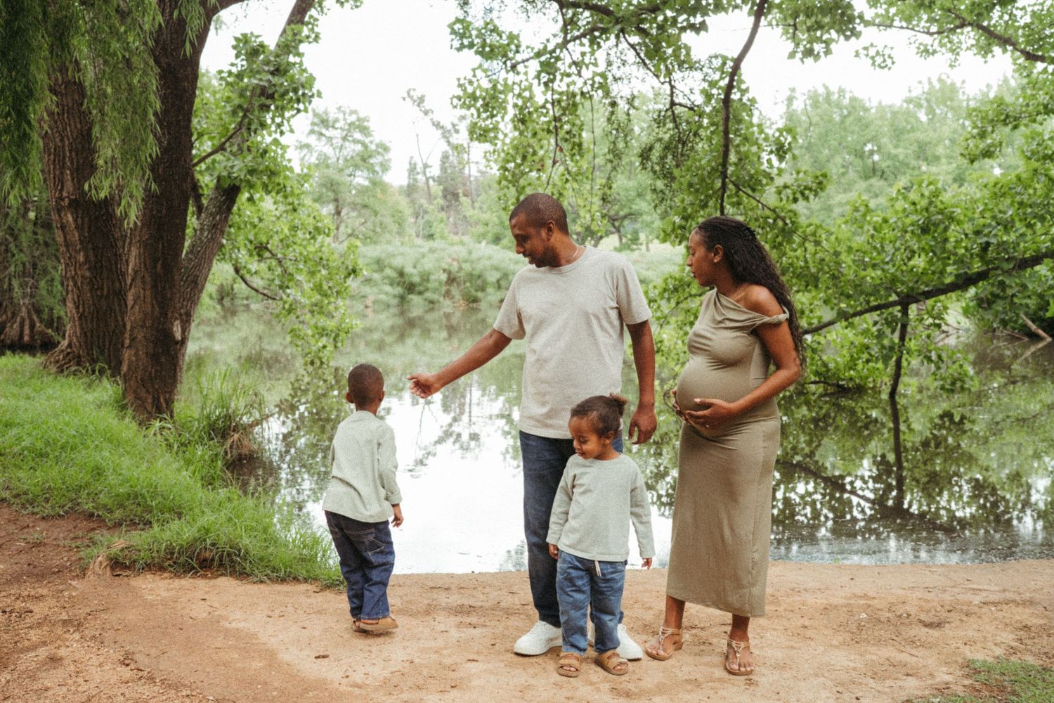 A family walking together on a wooded trail surrounded by lush green trees.