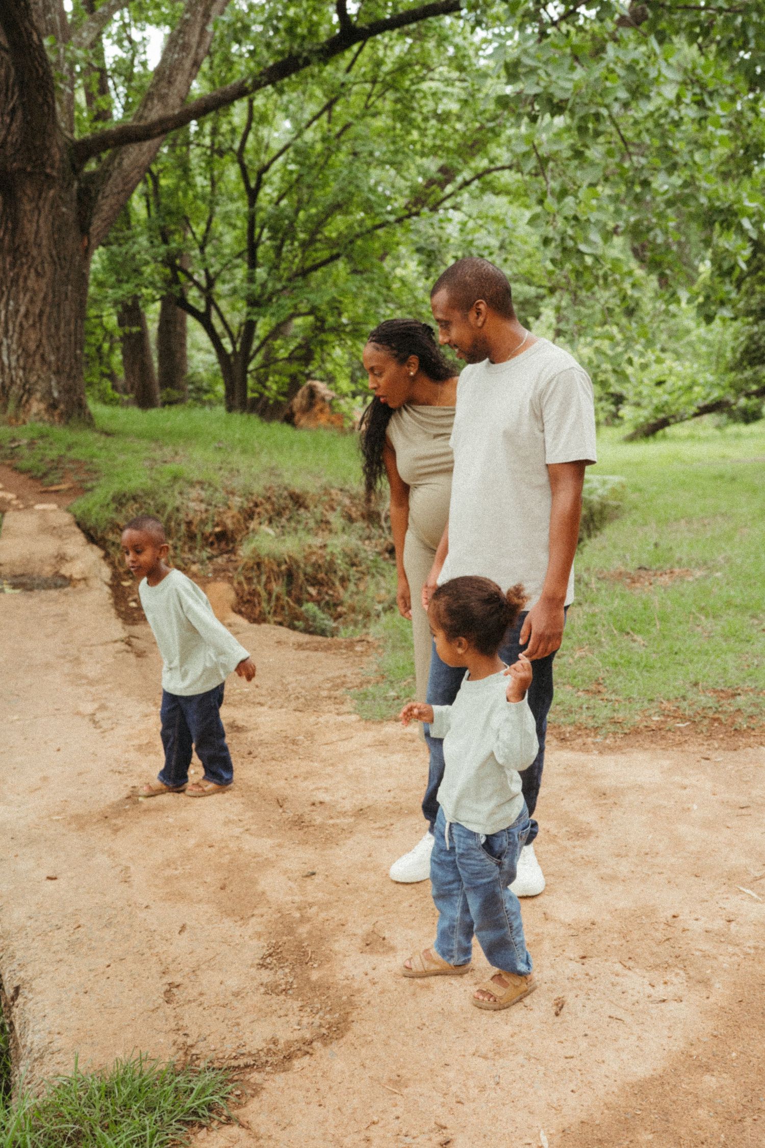 People walking and playing together on a dirt path through a wooded area.