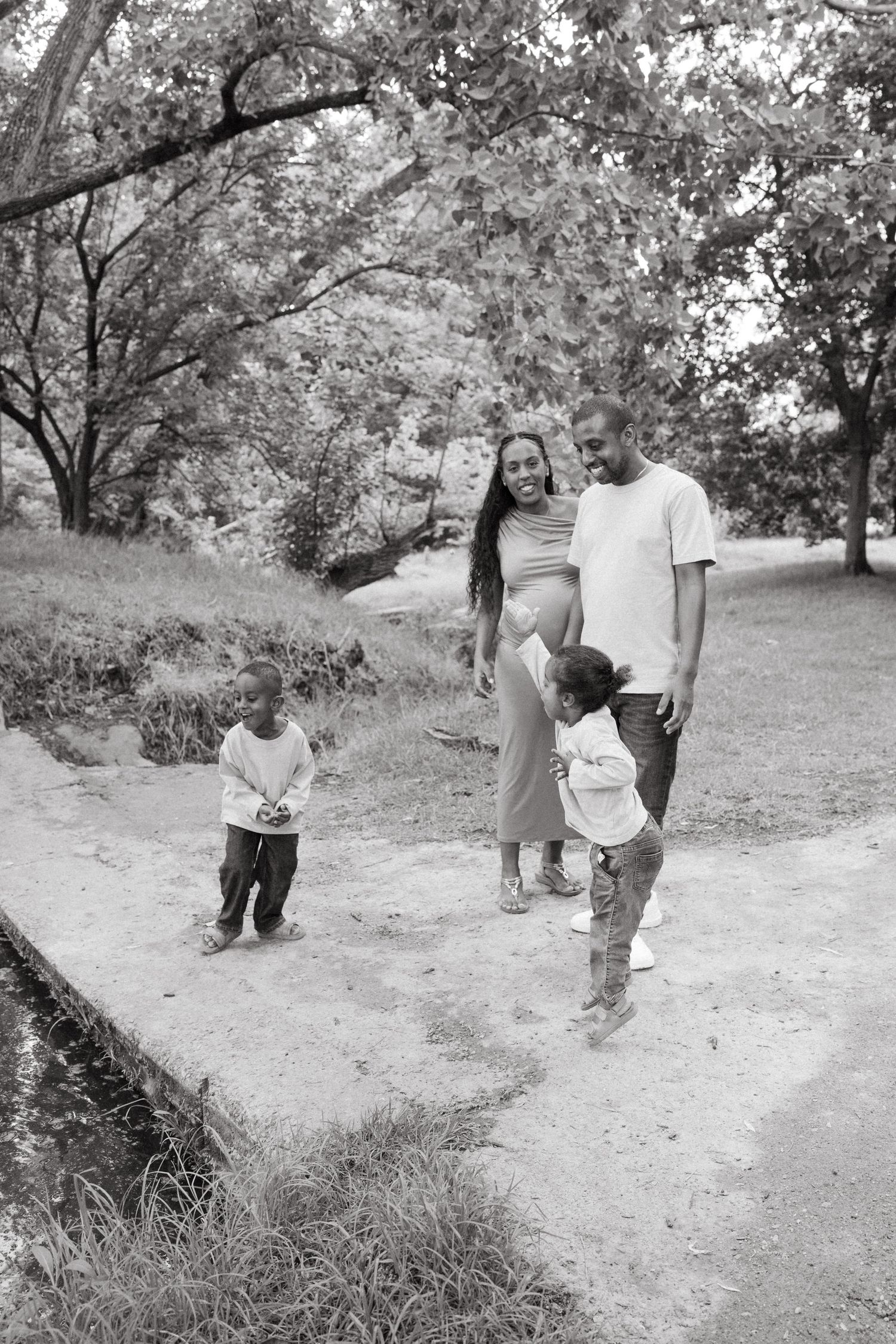Multiple shots of people walking and playing on a dirt trail in a park setting.