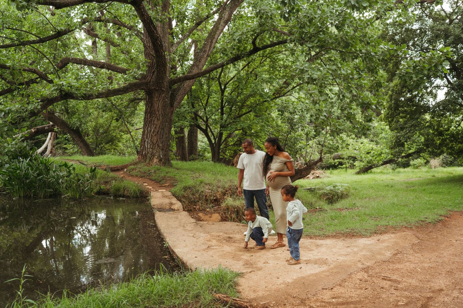 A dirt path winding through a green wooded area with people walking.