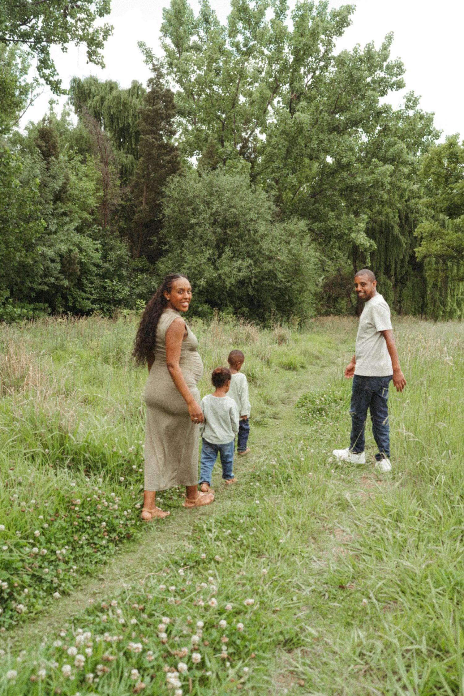 Group enjoying a casual stroll through a grassy field with trees on a sunny day.