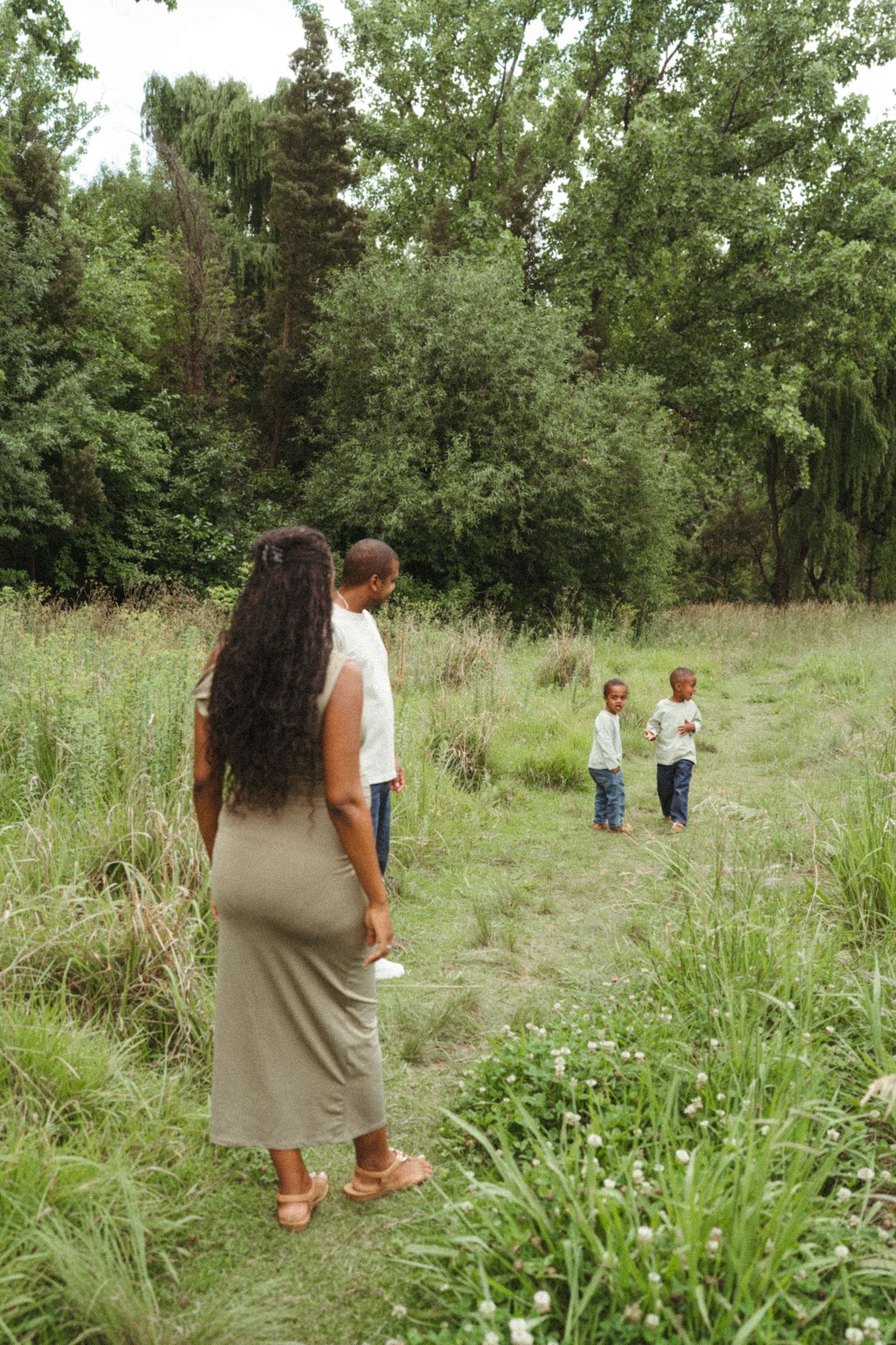 Family members walking and exploring a natural meadow landscape together.