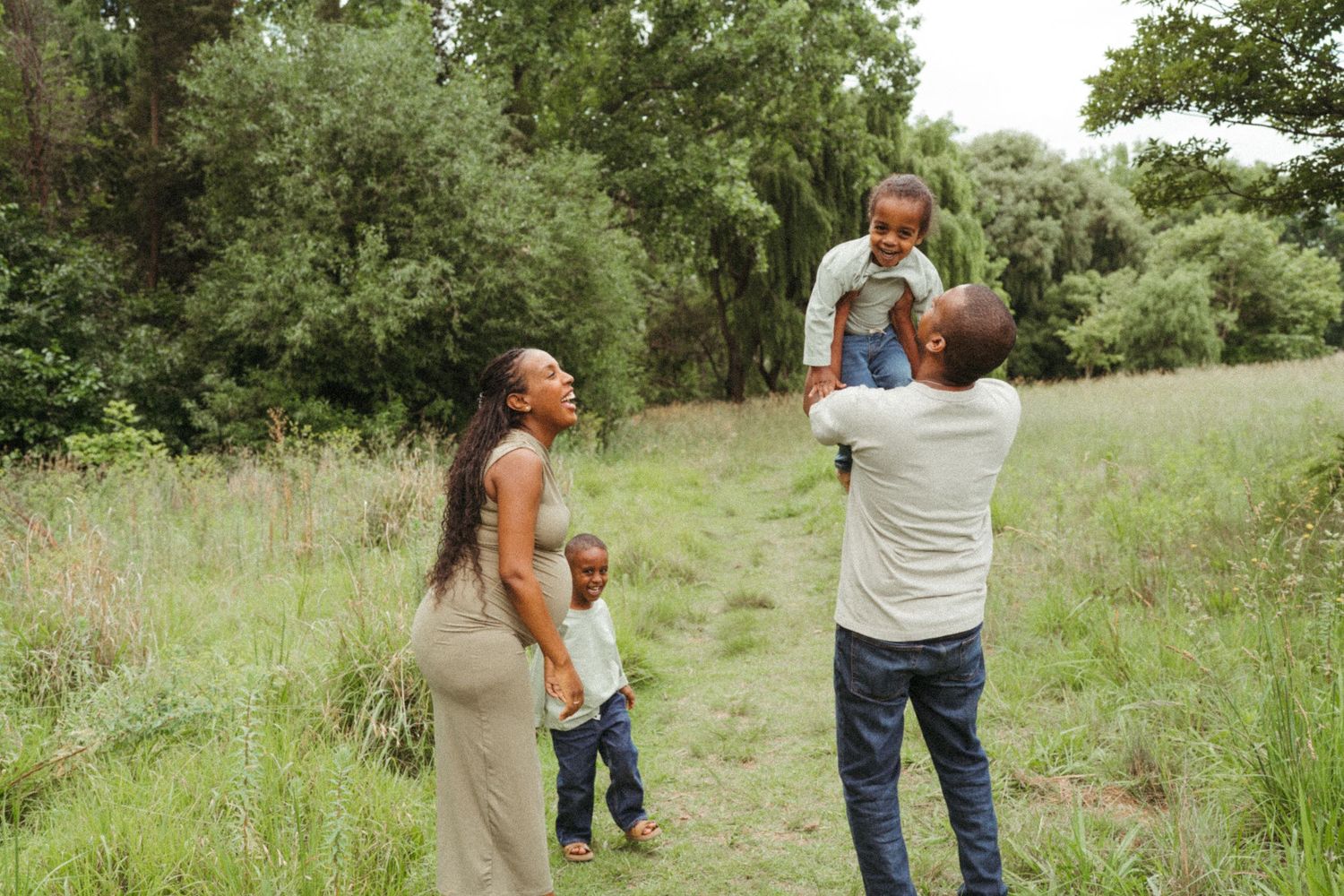 Family members walking and playing in a green summer meadow.