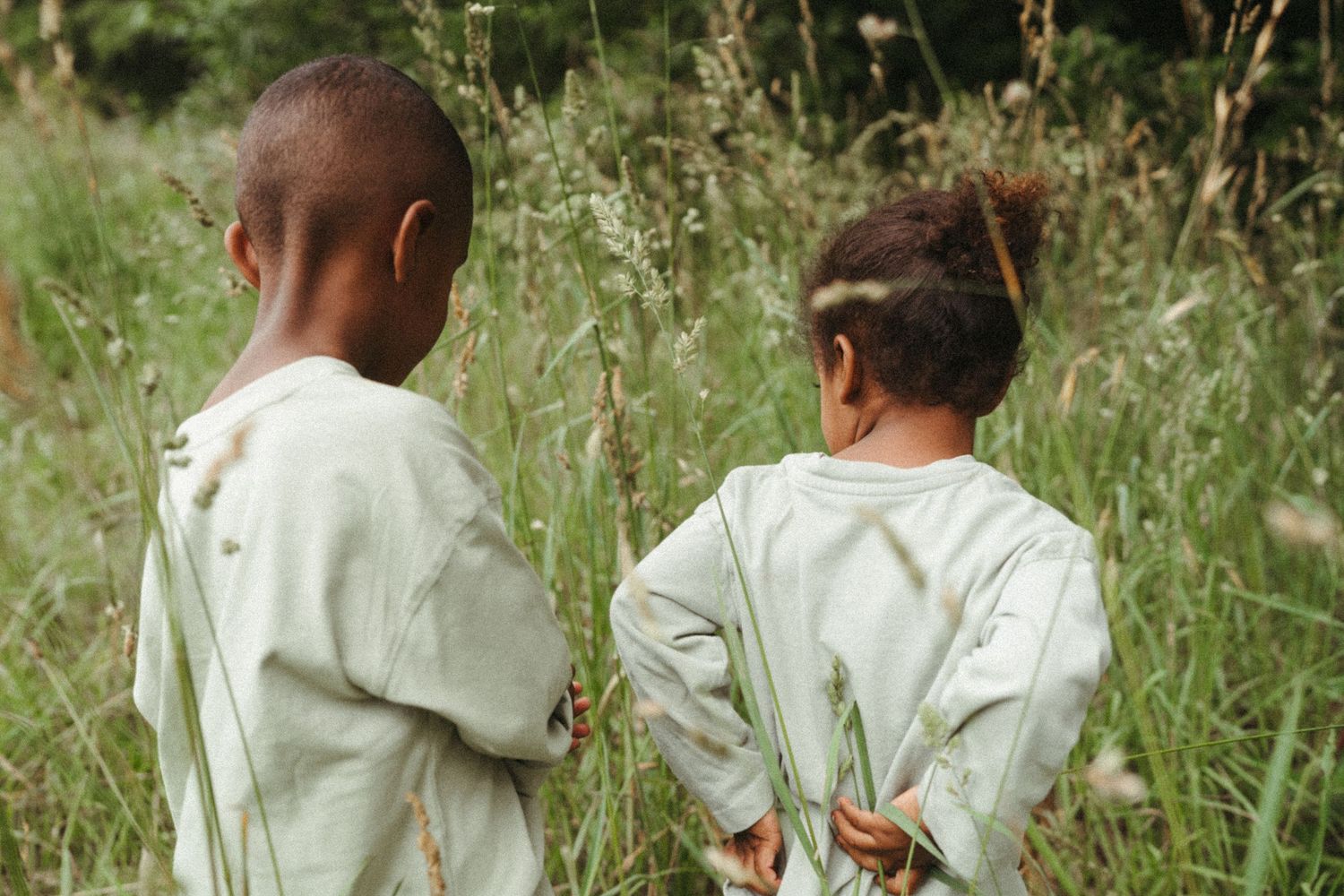 Family walking together through tall grass in a natural outdoor setting.