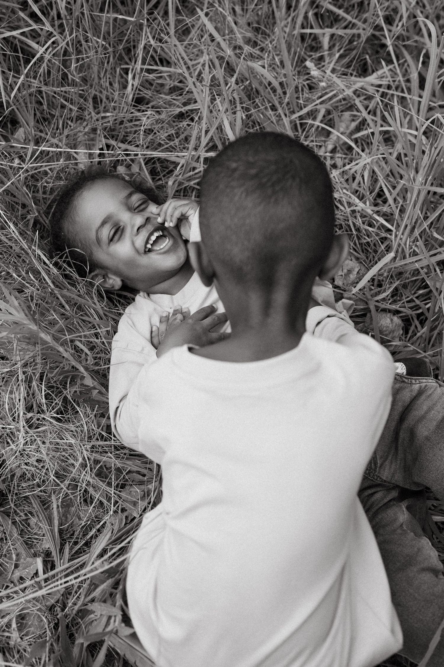 Two people lying in grass sharing an intimate black and white moment.