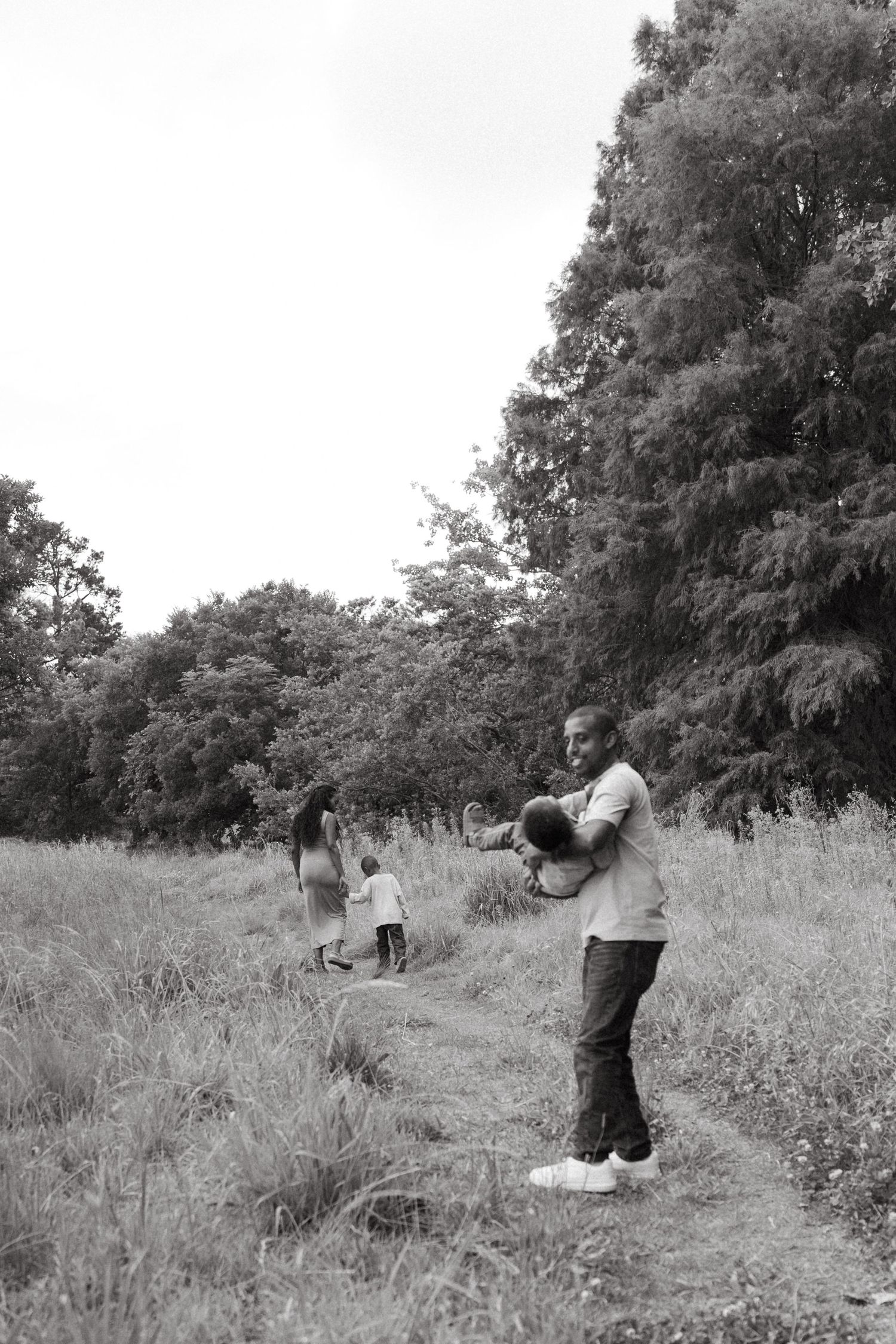 Black and white photo of family members embracing on a hillside path.