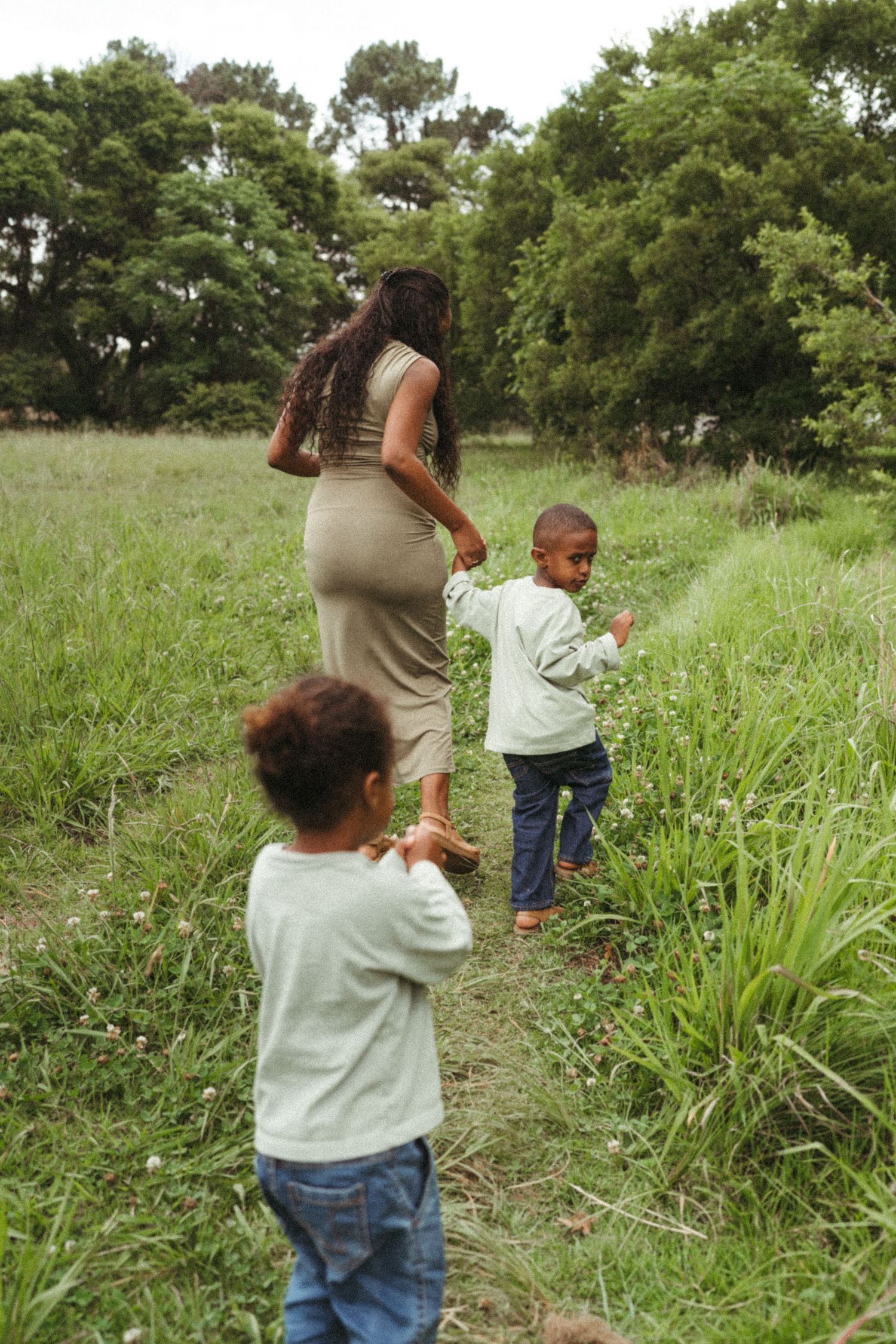 Family walking along a grassy path on a sunny afternoon.