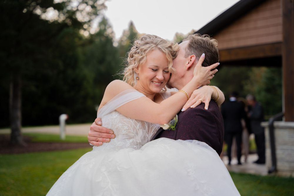 Joyful embrace between newlyweds outside rustic venue.
