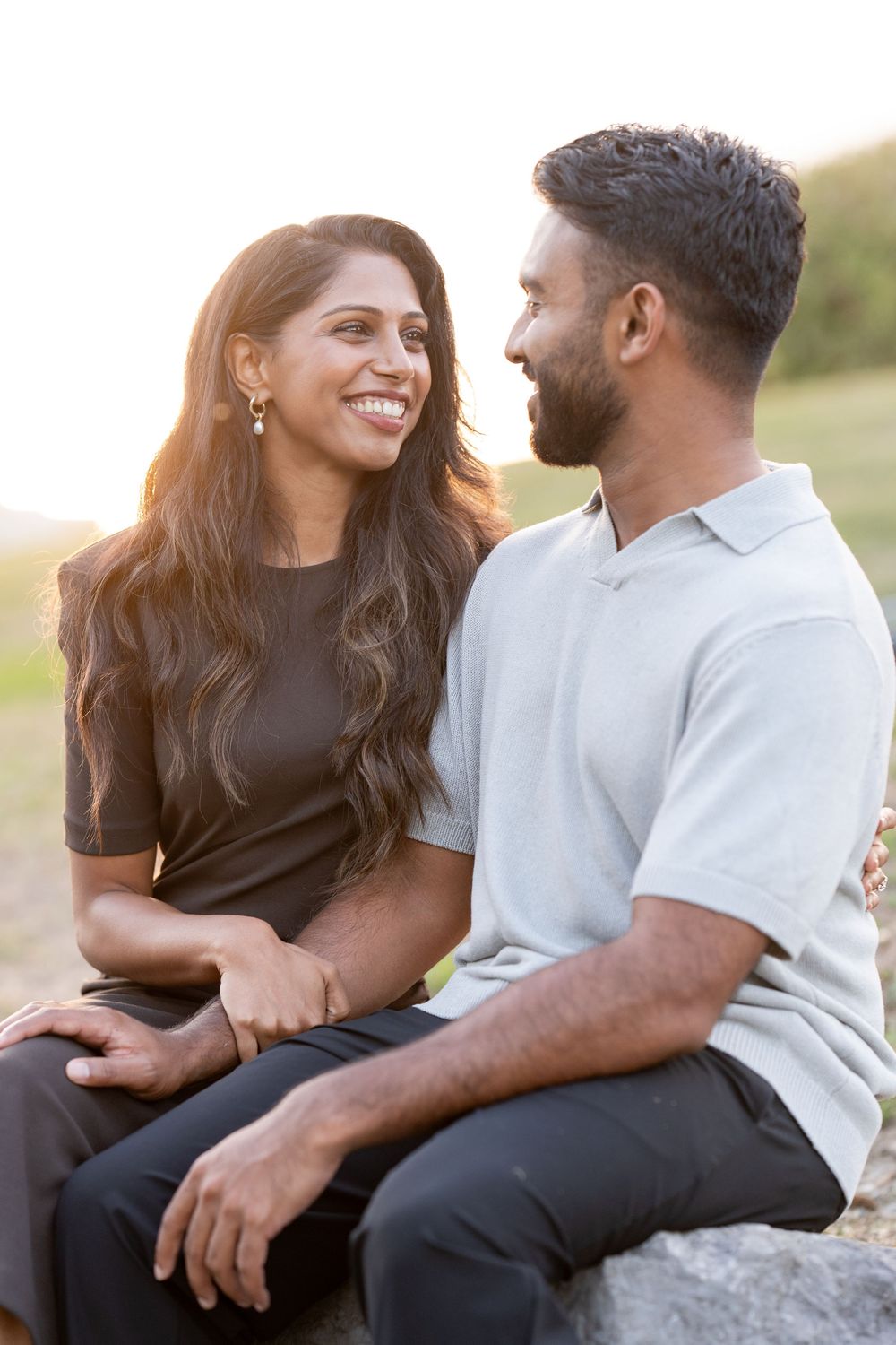 A couple sits together outdoors sharing intimate moments in a series of romantic sunset photos.