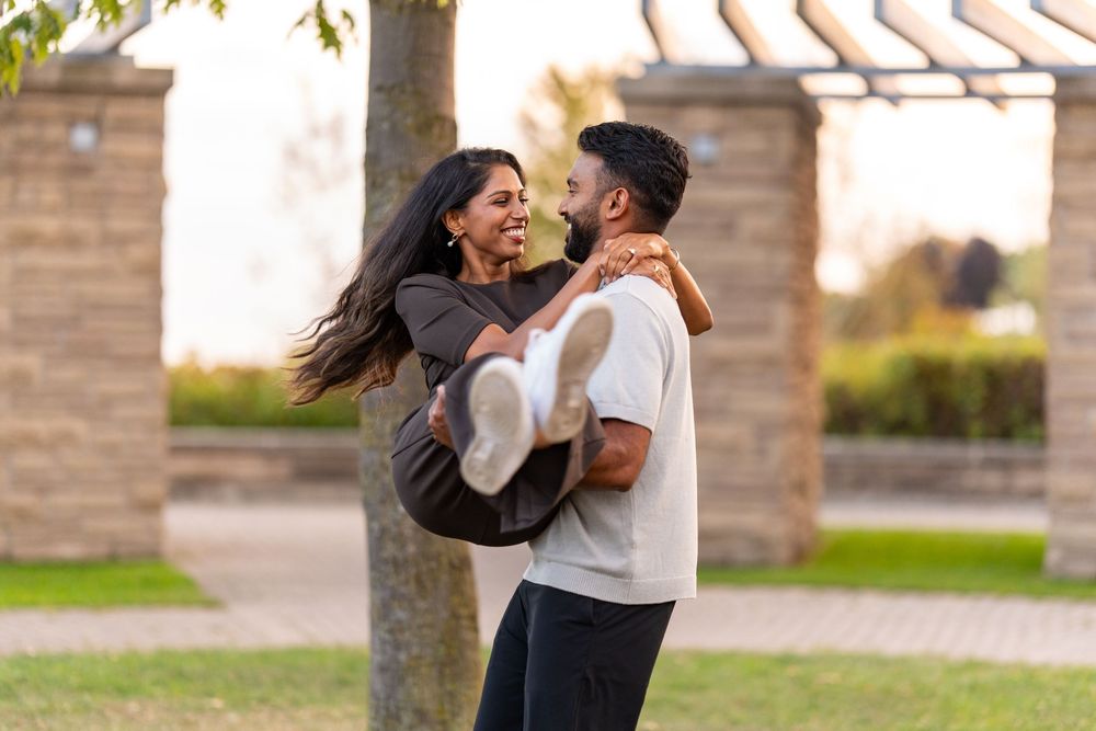 A couple embraces and dances together outdoors in a romantic moment at sunset.