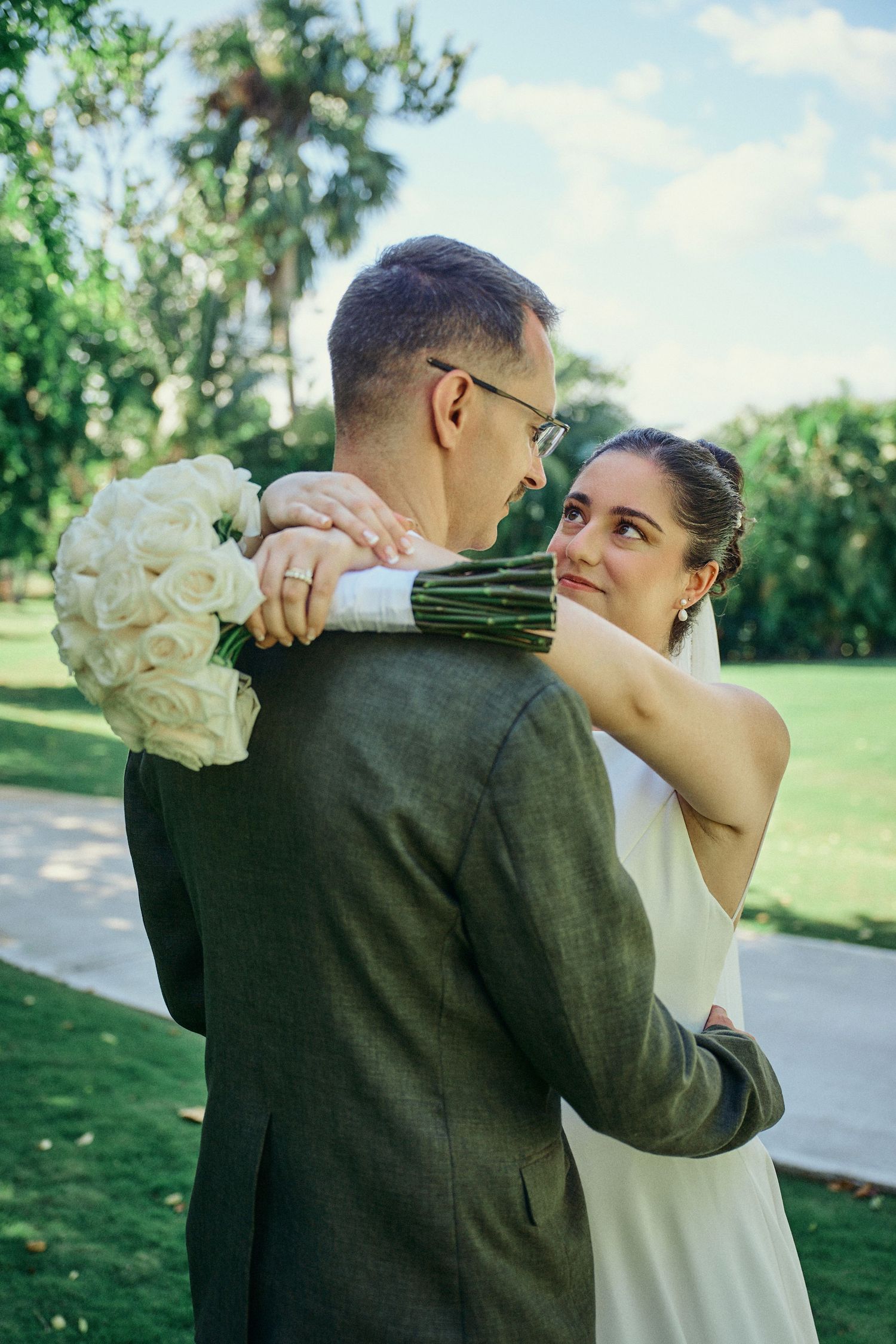 Romantic couple in formal black attire embrace against ruins in a lush garden setting. Jamaica Wedding Photographer
