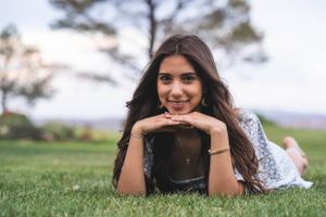 Person lying on green grass during an outdoor photo session.