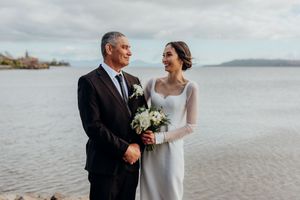 Joyful bride and dad sharing a smile with each other, lake Taupo in background, Proud dad, Beautiful asian, maori bride, designer dress,