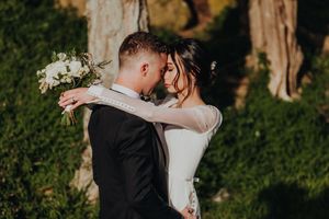 Happy bride and groom facing each other, tree in background, sunset light, romantic, Lake Taupo.
