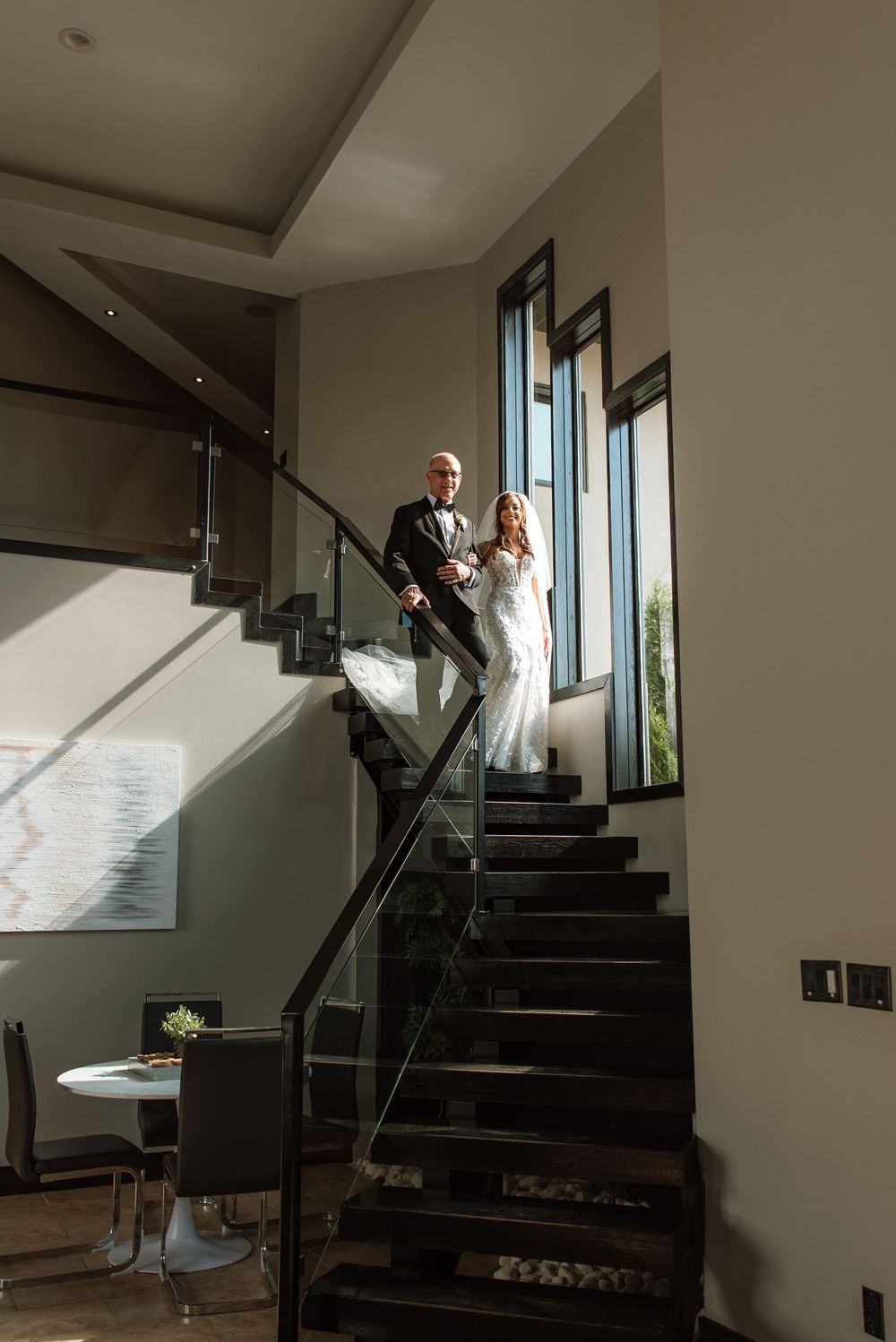 Modern staircase interior with dramatic lighting creates silhouettes during wedding day preparations.