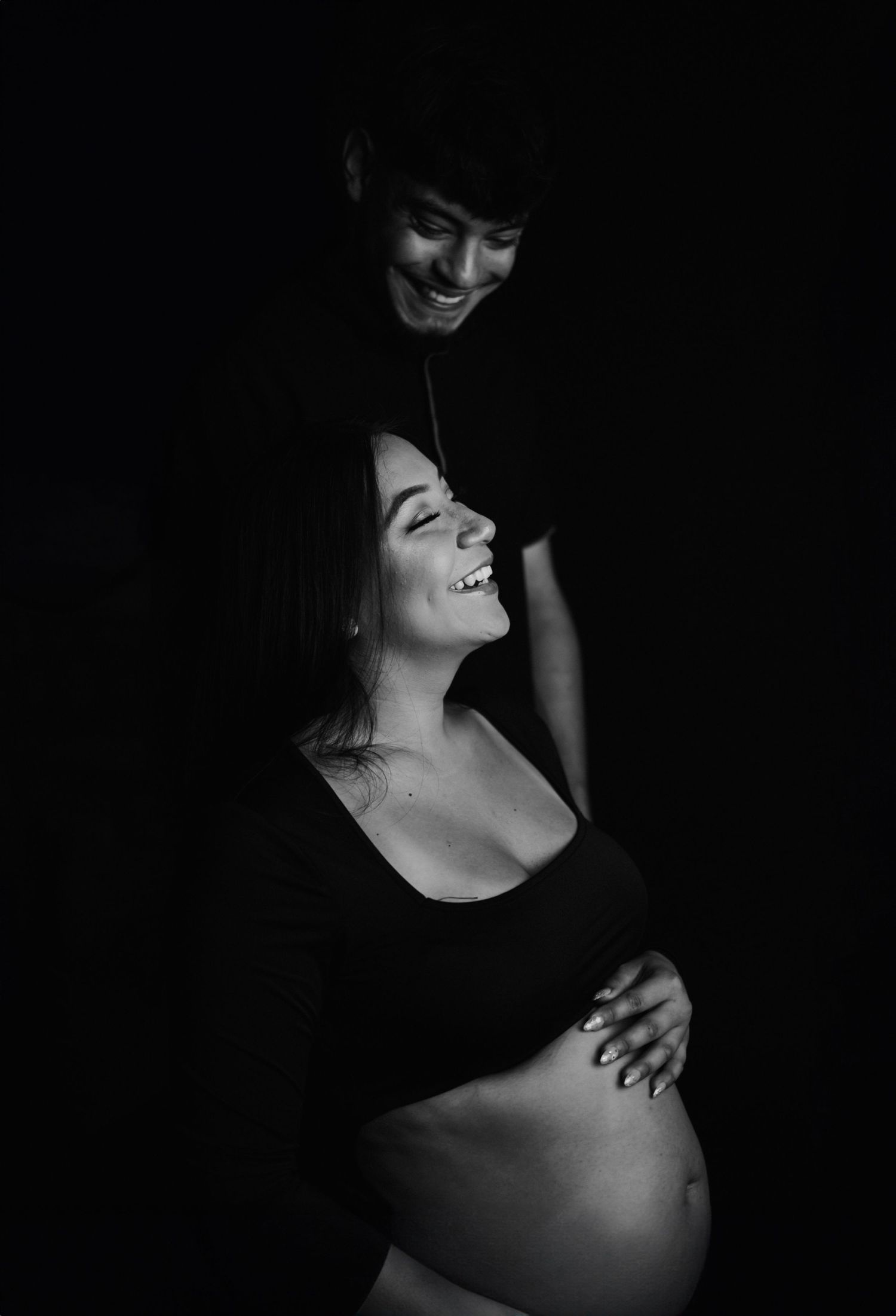 Artistic black and white maternity photo capturing an intimate moment between two people.