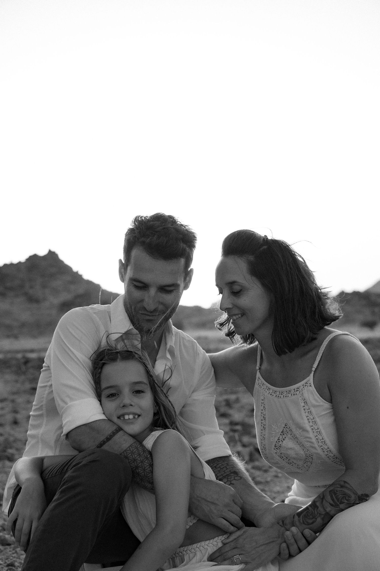 A black and white photo sequence showing a family embracing and playing together outdoors.