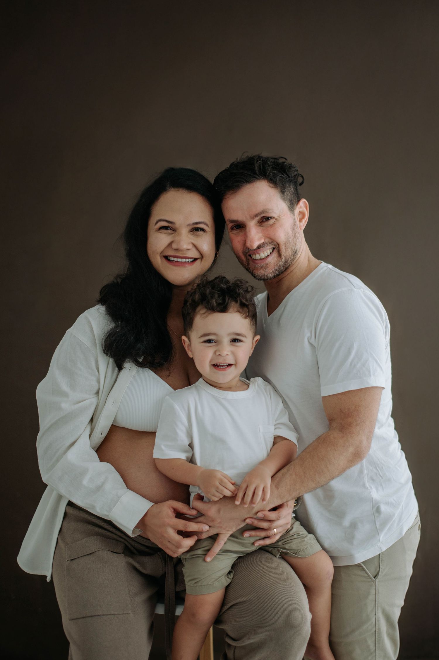 Family sitting together on a white blanket in a natural outdoor setting.