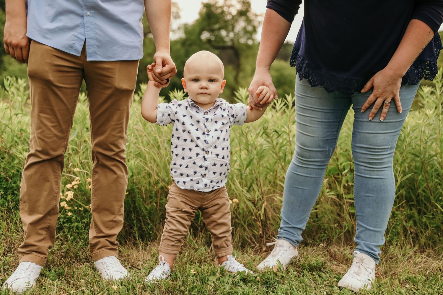 Row of legs and feet showing family members standing together in casual attire.