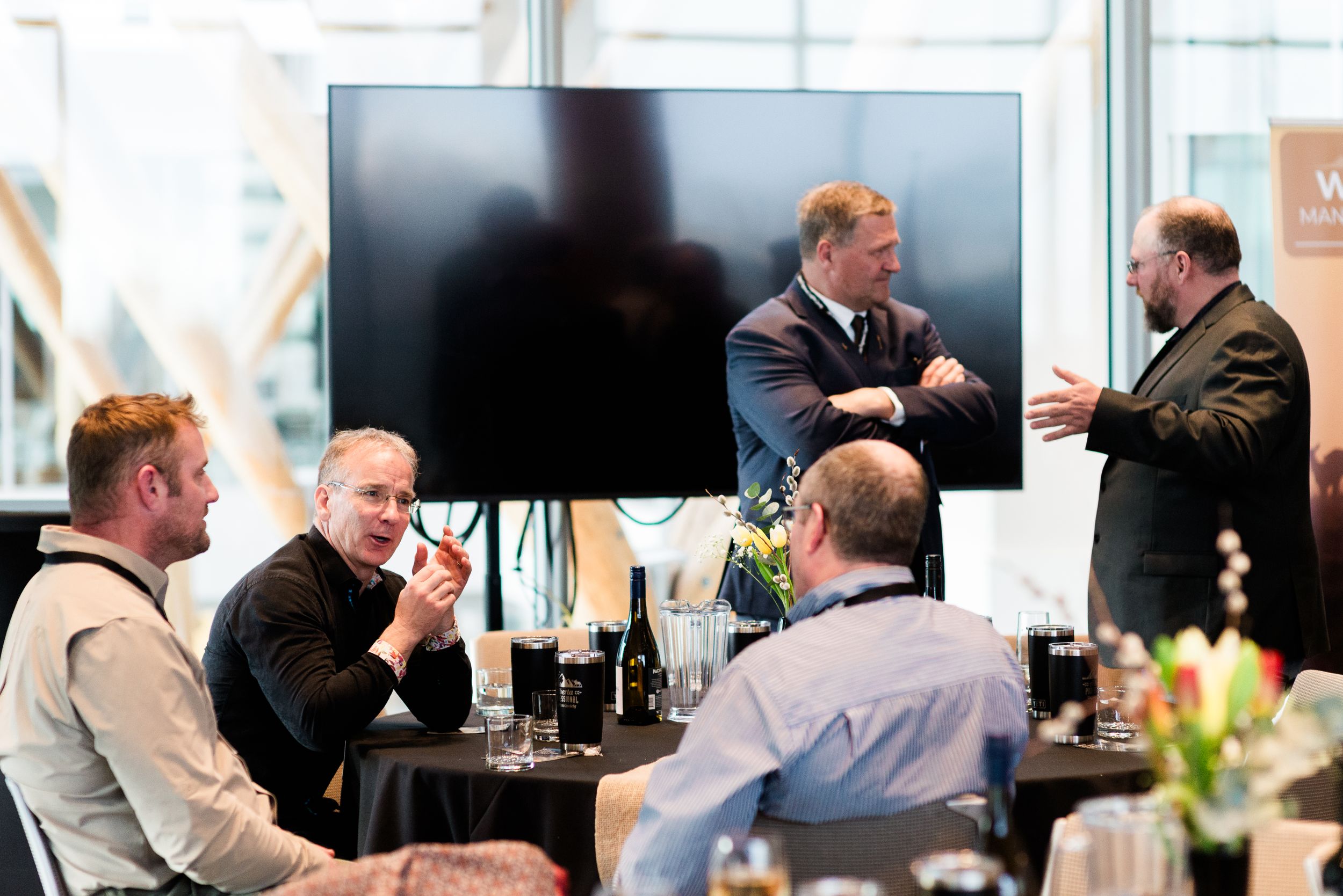 Business professionals gathered around a table with drinks for a casual meeting discussion.