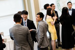 Group of professionally dressed people engaged in conversation at a formal networking event.