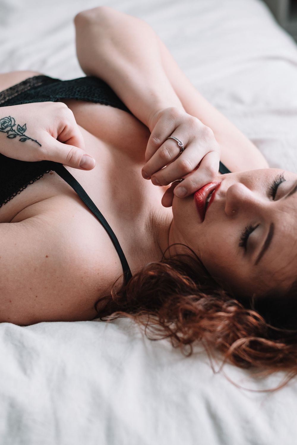 Intimate boudoir photography featuring delicate lace details and rose tattoo artwork.