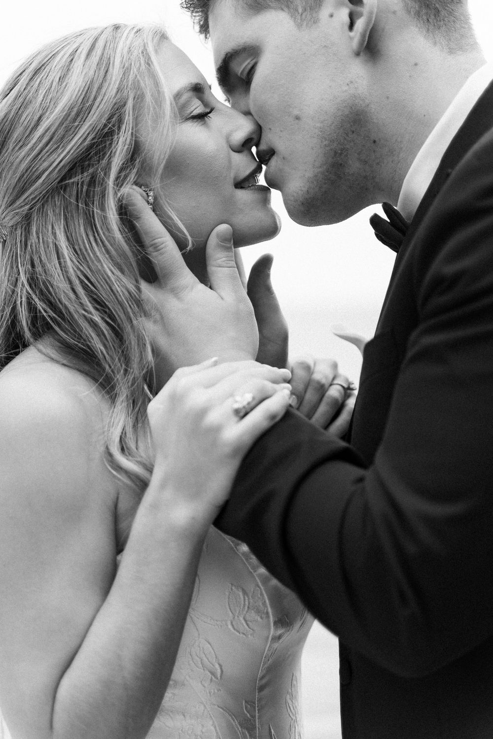 A romantic black and white photo series showing tender close-up moments between a bride and groom sharing intimate kisses.