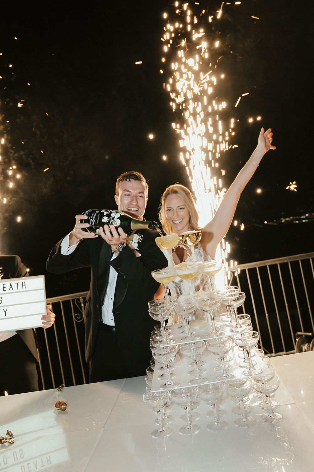 A champagne tower sparkles with pyrotechnics as a couple celebrates at their wedding reception.