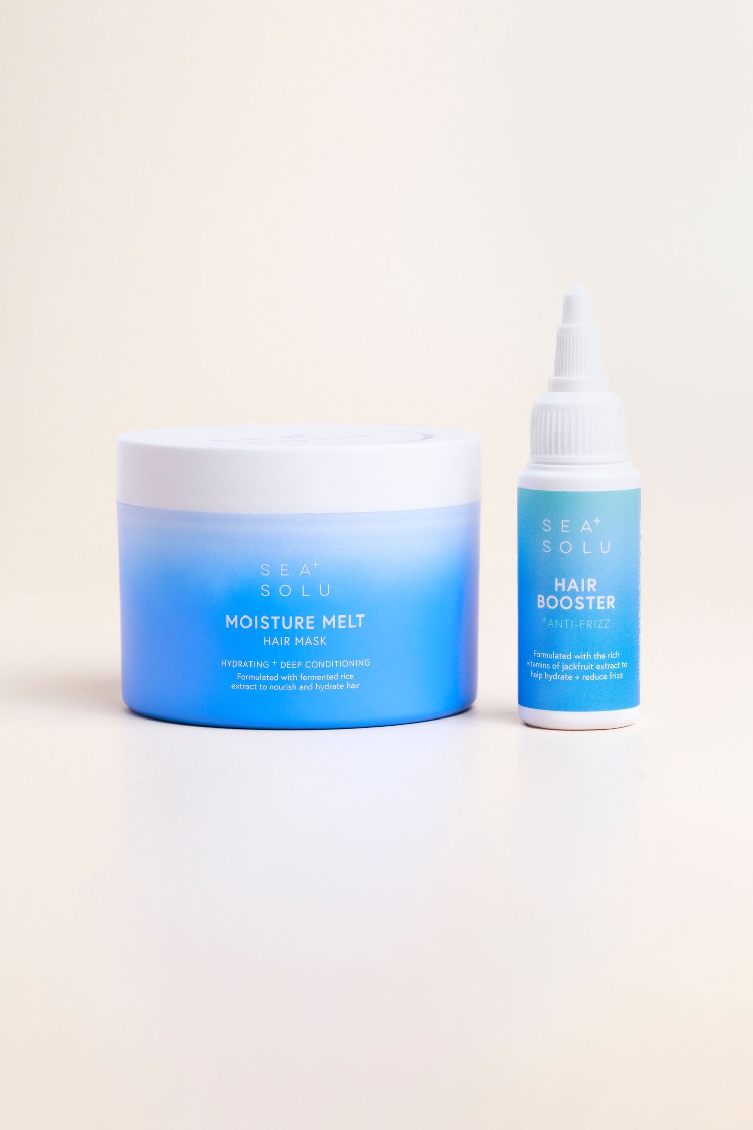 Blue hair care products including moisture melt and hair booster against beige background with soft shadows.
