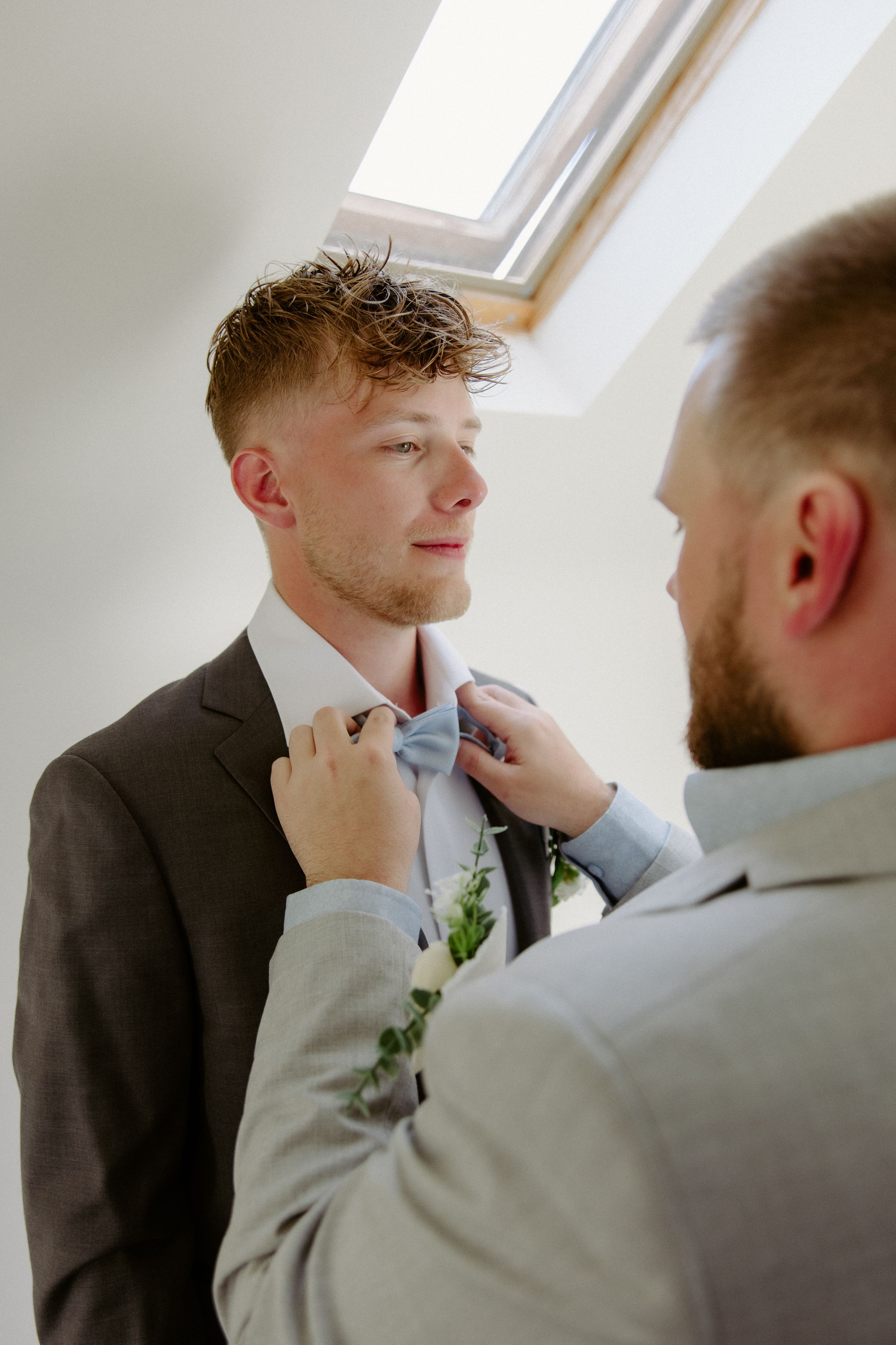 Groomsmen fixes grooms tie, getting ready portraits wedding photography Moncton New Brunswick, AirBnB elopement in Pugwash NS