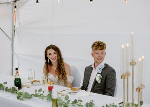 bride and groom react during speeches in an outdoor summer wedding, backyard tent wedding in Pugwash Nova Scotia microwedding elopement