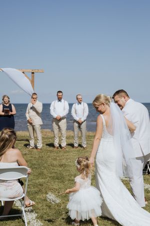 Bride walks down aisle during outdoor summer wedding ceremony in Cap Pele New Brunswick, Shediac wedding photography full sun natural light