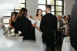 bride and groom hold hands during wedding ceremony, intimate elopement at Tire Shack Brewery event space in Moncton New Brunswick, film vibe